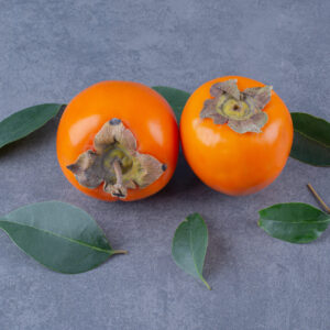 Persimmon fruits and leaves, on the marble background. High quality photo