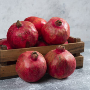 A wooden basket full of sweet ripe pomegranate fruits. High quality photo